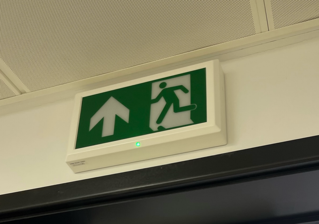 Security-integrated fire exit sign illustrating a building-wide lockdown solution for offices and industrial sites in the Midlands.