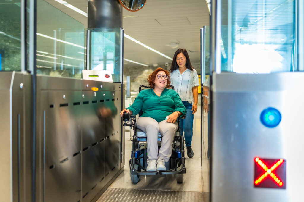 A wheelchair user passing through a DDA-compliant wide-access security gate in a Coventry commercial building, ensuring inclusive building access.