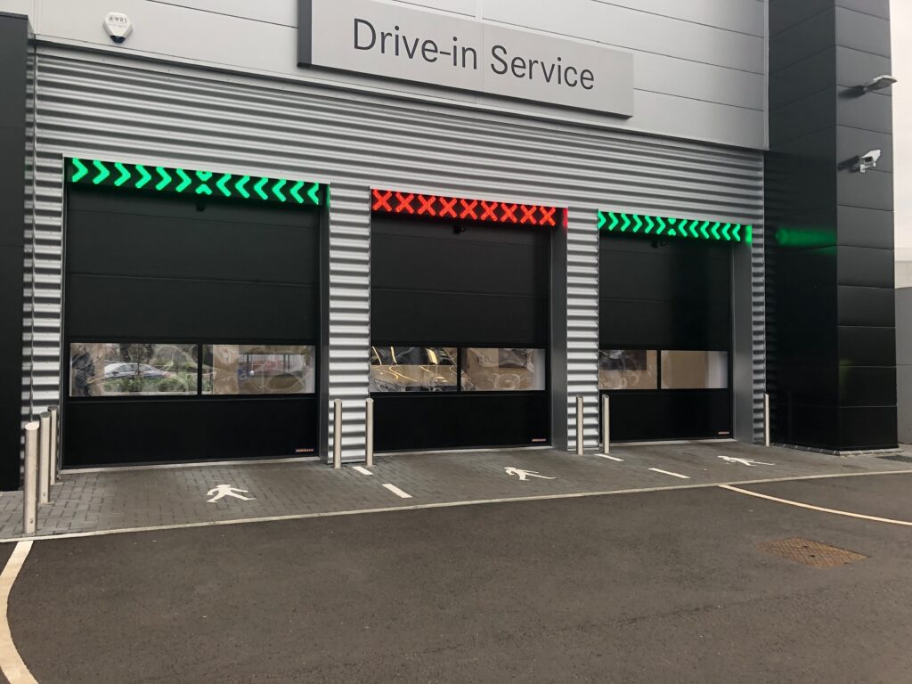Automated commercial security gates at a drive-in service bay with green and red LED traffic signals.